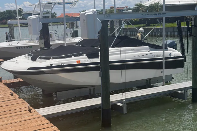Slide: The Image of 2008 NauticStar 210 DC Sport Deck boat docked on lift, covered and ready for use. - 20