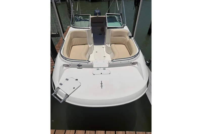 Slide: The Image of 2008 NauticStar 210 DC Sport Deck boat with beige seating, docked on calm water. - 4