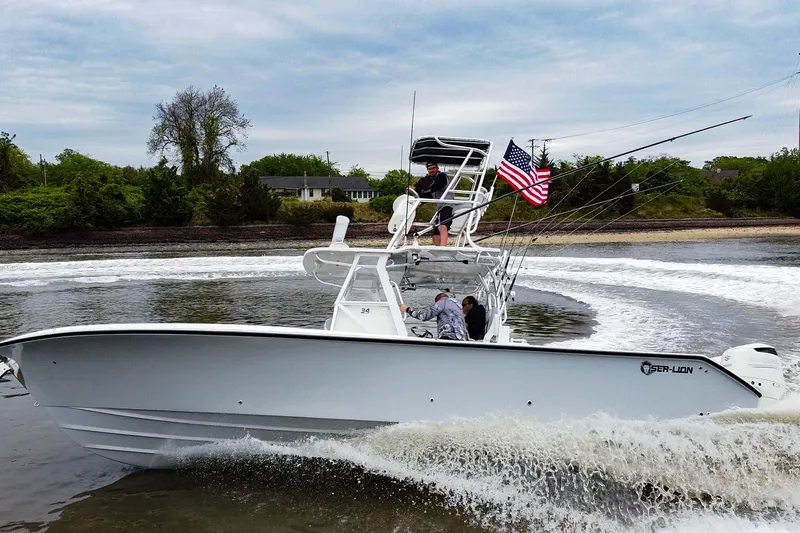 Slide: The Image of 2020 Sea-Lion 34 TE boat cruising with American flag, near lush shoreline. - 1