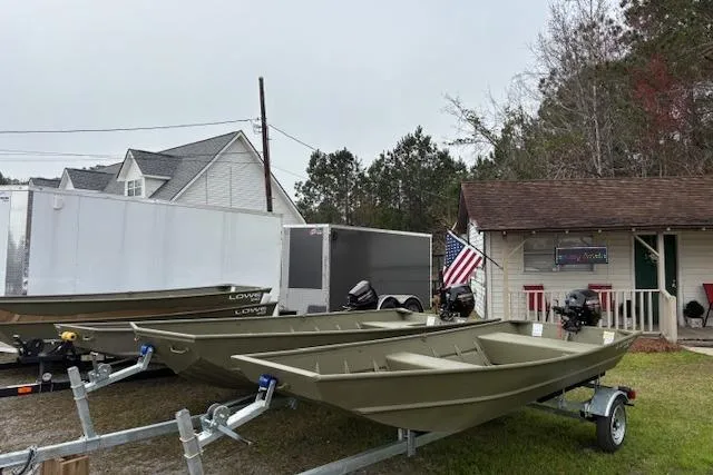 Slide: The Image of 2026 Lowe L1436L Jon boats on trailers outside a shop with American flag. - 3