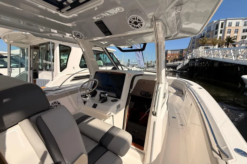 Slide: The Image of 2026 Pursuit S 328 Sport boat interior with modern helm and seating at a marina. - 15