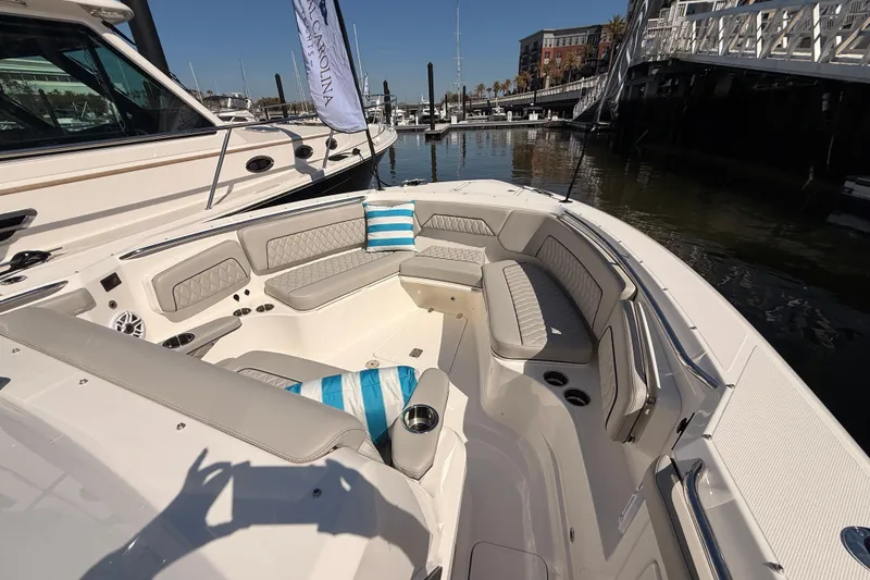 Slide: The Image of 2026 Pursuit S 328 Sport boat interior with cushioned seating and striped pillows at a marina. - 17