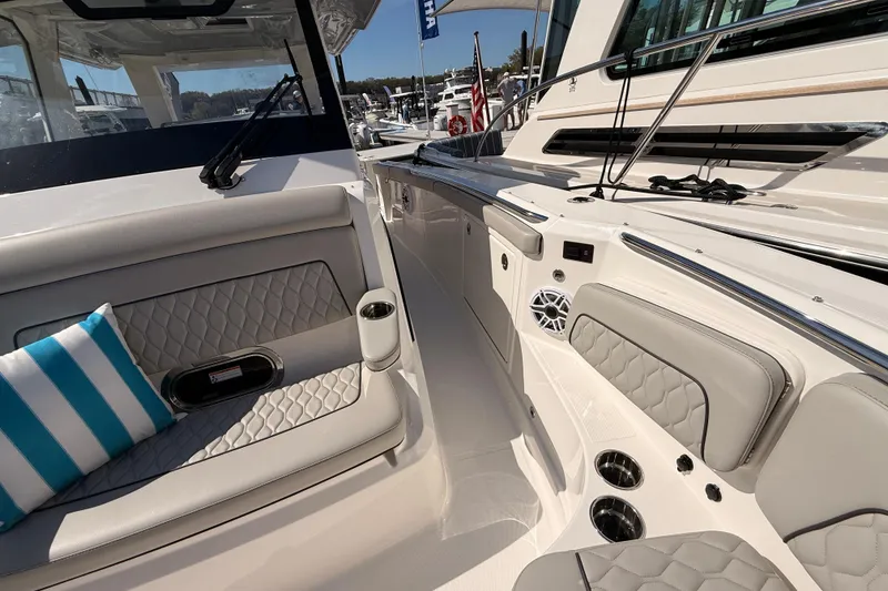 Slide: The Image of 2026 Pursuit S 328 Sport boat interior with cushioned seating and striped pillow. - 20