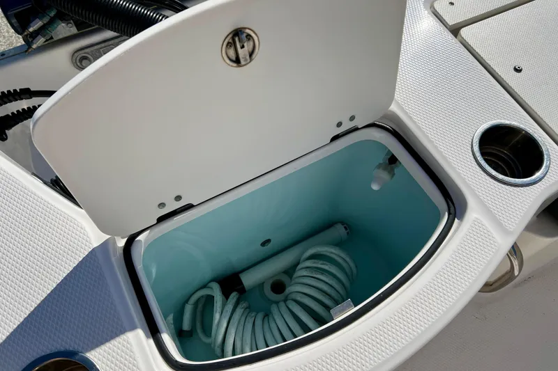 Slide: The Image of Open storage compartment on 2024 Robalo 206 Cayman boat, featuring coiled hose. - 11