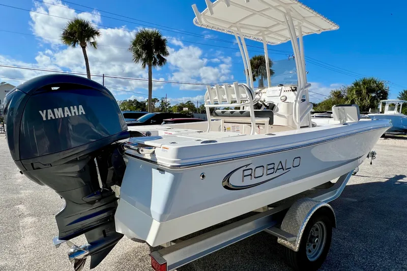 Slide: The Image of 2024 Robalo 206 Cayman boat with Yamaha engine on trailer, palm trees in background. - 6