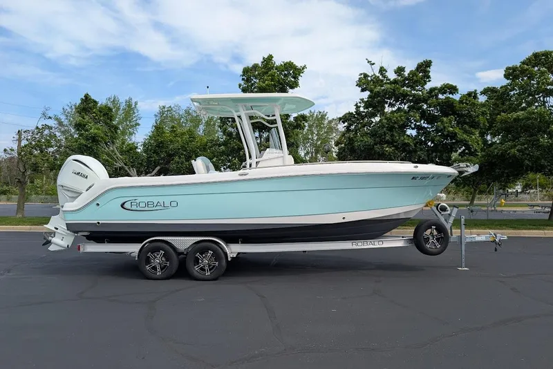 The Image of 2022 Robalo R242 Explorer boat on trailer, parked outdoors with trees in background. - 0