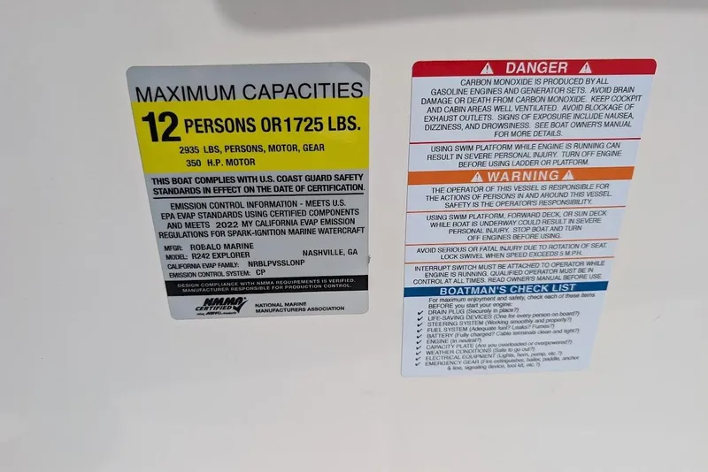 Slide: The Image of Capacity and safety labels on 2022 Robalo R242 Explorer boat, detailing maximum load and warnings. - 40