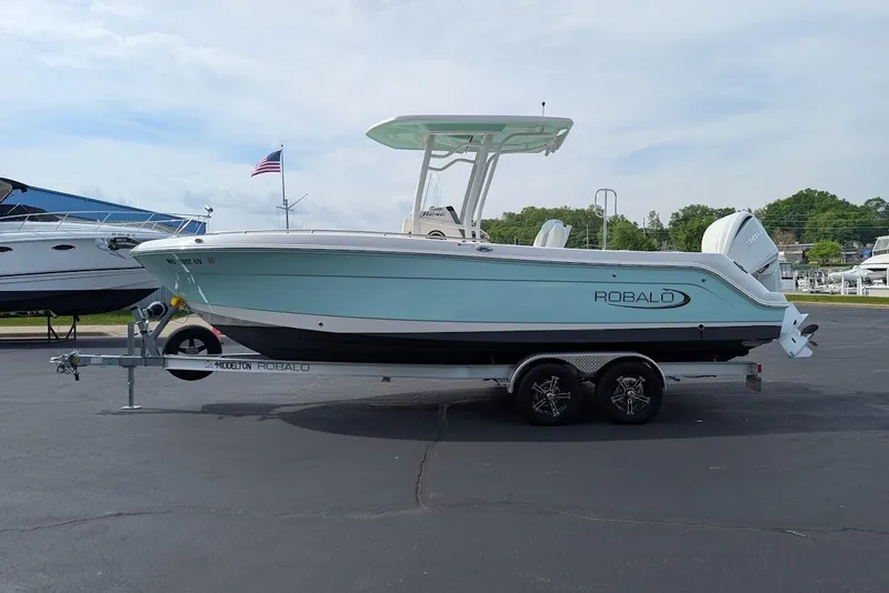 Slide: The Image of 2022 Robalo R242 Explorer boat on trailer, parked outdoors with American flag in background. - 5