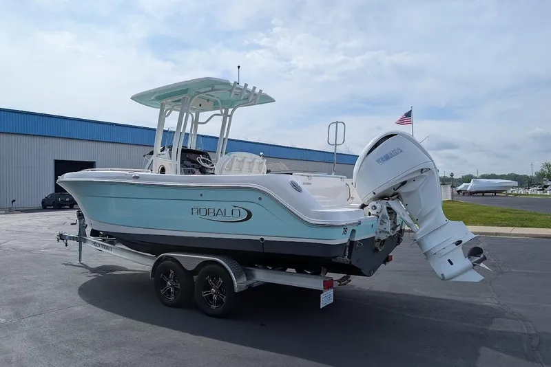 Slide: The Image of 2022 Robalo R242 Explorer boat on trailer, parked outdoors near a blue building. - 6