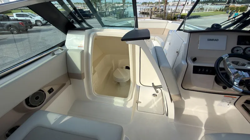 Slide: The Image of The image shows the cockpit of a 2027 Boston Whaler 240 Vantage with a small bathroom. - 23