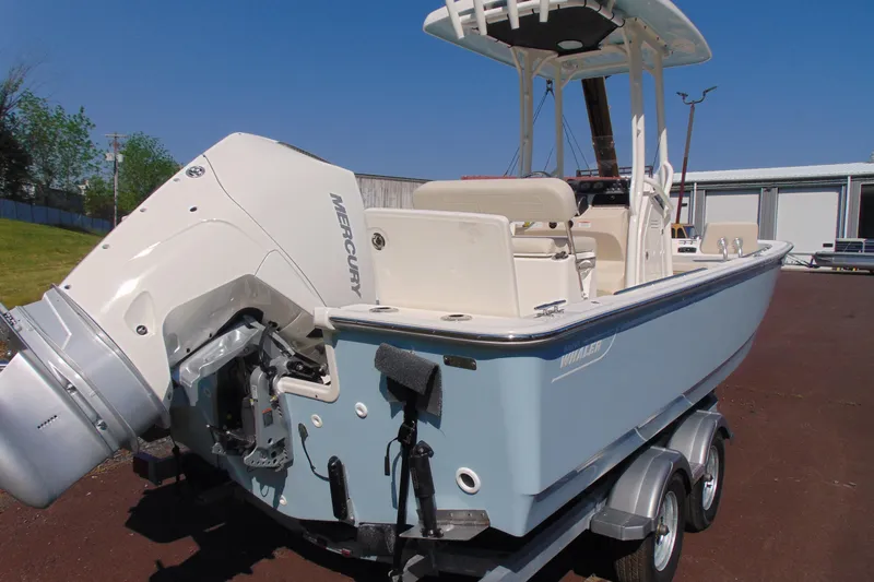Slide: The Image of 2026 Boston Whaler 210 Montauk boat with Mercury engine on trailer, outdoor setting. - 2