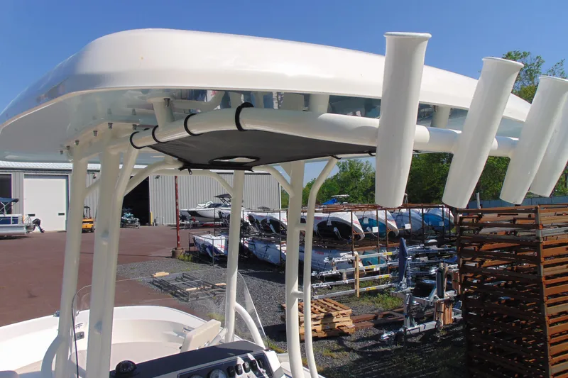 Slide: The Image of 2026 Boston Whaler 210 Montauk boat with T-top and rod holders in a marina setting. - 9