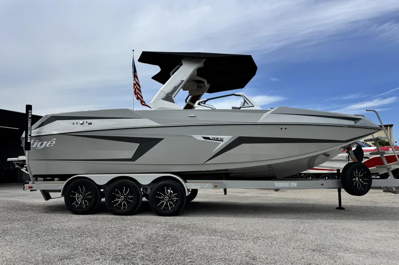 Slide: The Image of 2026 Tigé 24RZX boat on trailer, sleek design, American flag, overcast sky. - 3