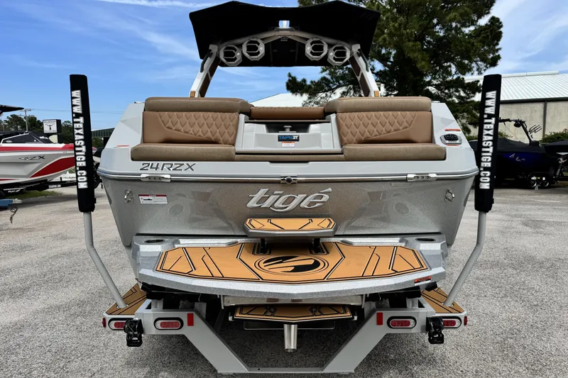 Slide: The Image of 2026 Tigé 24RZX boat rear view with tan seating and teak-style swim platform. - 5