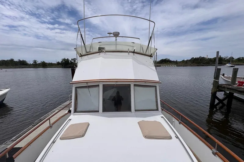 Slide: The Image of 1989 Grand Banks 42 Motoryacht docked on a calm river under a cloudy sky. - 10