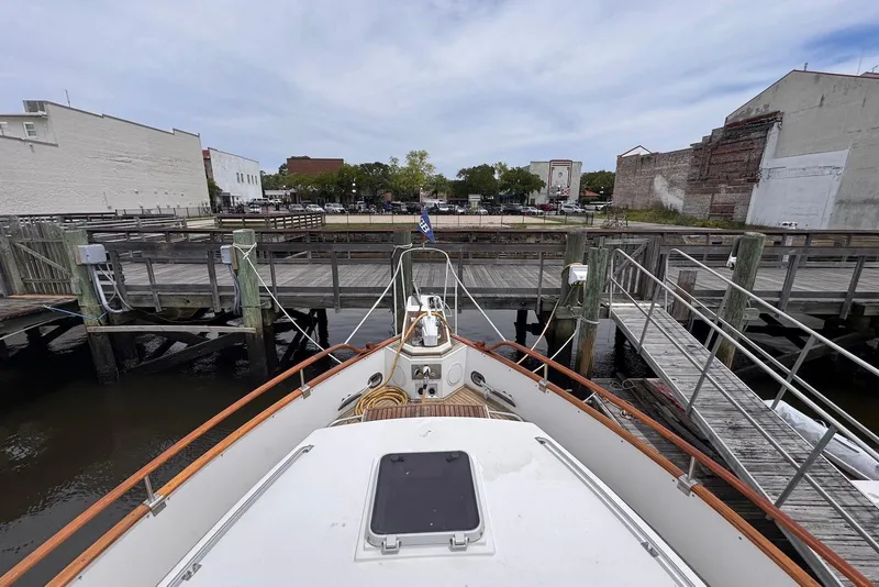 Slide: The Image of 1989 Grand Banks 42 Motoryacht docked at a wooden pier, urban backdrop. - 11