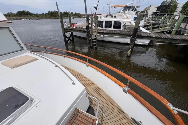 Slide: The Image of 1989 Grand Banks 42 Motoryacht docked at a marina, showcasing wooden deck and railing. - 13