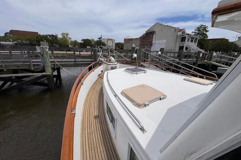 Slide: The Image of 1989 Grand Banks 42 Motoryacht docked, showcasing teak deck and marina surroundings. - 15