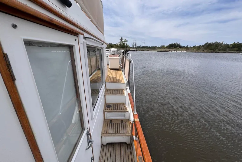 Slide: The Image of 1989 Grand Banks 42 Motoryacht deck view on calm water, showcasing classic design. - 16