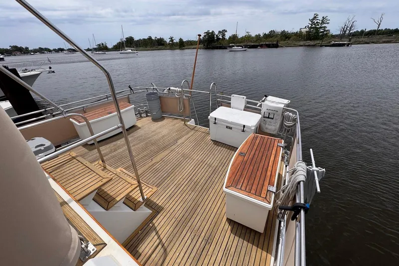 Slide: The Image of 1989 Grand Banks 42 Motoryacht deck with wooden flooring, docked by a serene river. - 17