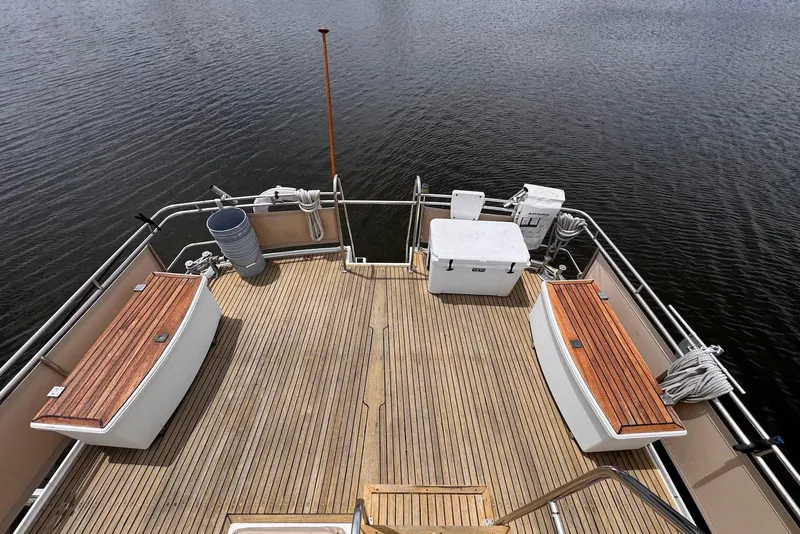 Slide: The Image of 1989 Grand Banks 42 Motoryacht deck with wooden benches and storage, overlooking calm water. - 18