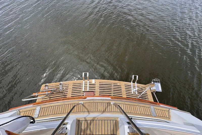 Slide: The Image of 1989 Grand Banks 42 Motoryacht stern view with wooden deck and water backdrop. - 20