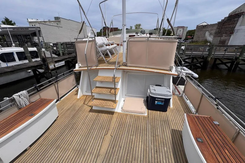 Slide: The Image of 1989 Grand Banks 42 Motoryacht deck with wooden flooring and seating at a marina. - 23