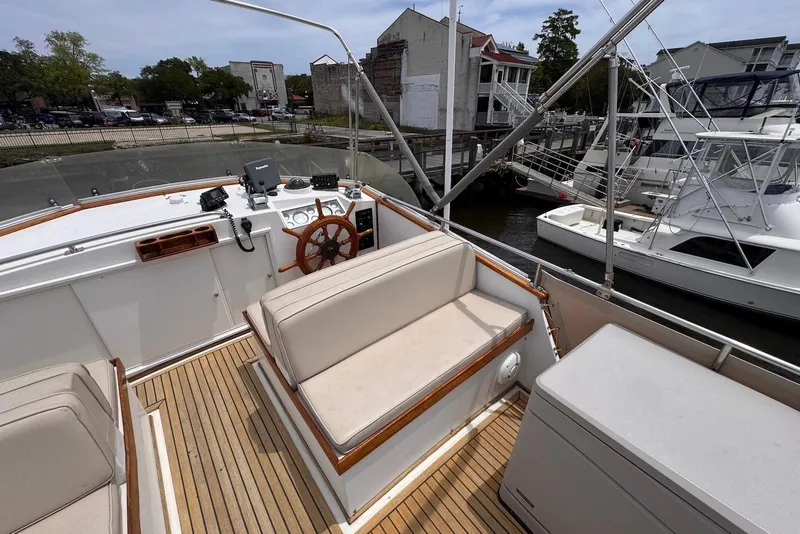 Slide: The Image of 1989 Grand Banks 42 Motoryacht helm with wooden wheel and cushioned seating at dock. - 27
