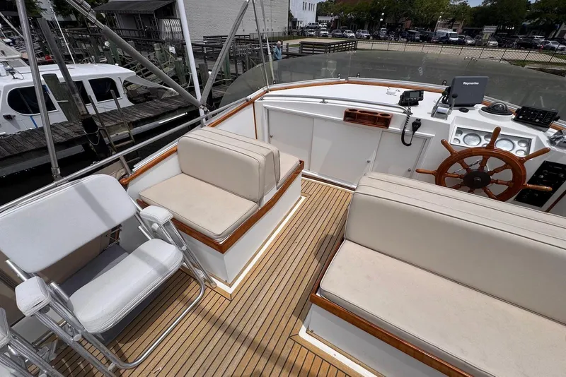 Slide: The Image of 1989 Grand Banks 42 Motoryacht helm with wooden wheel, cushioned seating, and navigation equipment. - 28