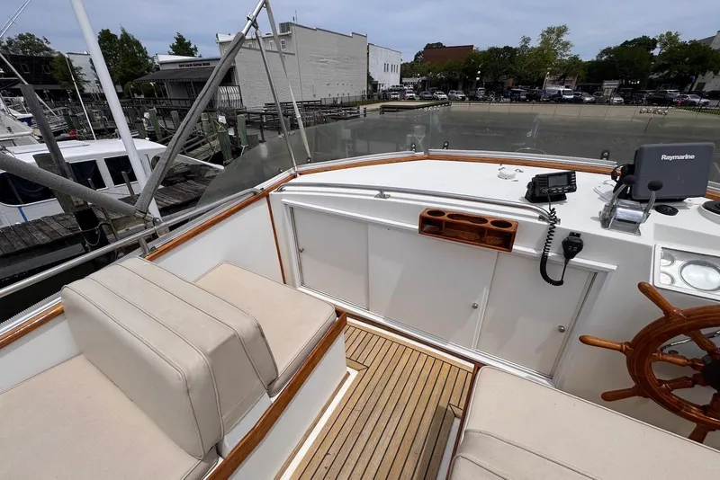 Slide: The Image of 1989 Grand Banks 42 Motoryacht helm with wooden wheel, Raymarine equipment, and cushioned seating. - 29