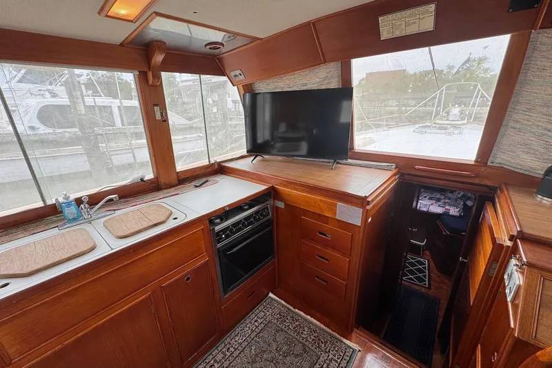 Slide: The Image of 1989 Grand Banks 42 Motoryacht interior with kitchen, TV, and wooden cabinetry. - 33