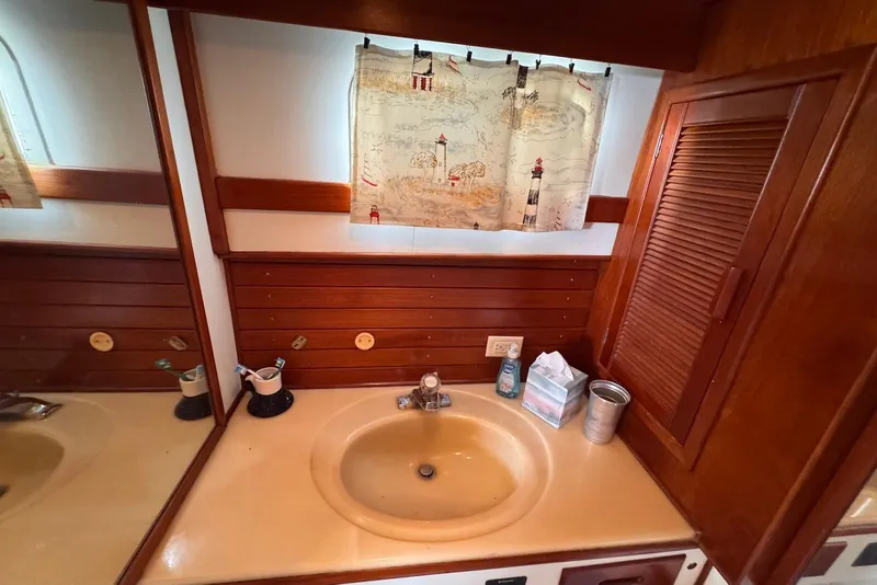 Slide: The Image of 1989 Grand Banks 42 Motoryacht bathroom with wooden cabinetry and nautical-themed curtain. - 51