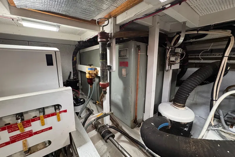 Slide: The Image of Engine room of a 1989 Grand Banks 42 Motoryacht, showcasing mechanical components and piping. - 63