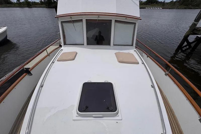 Slide: The Image of 1989 Grand Banks 42 Motoryacht deck view with cushions and hatch, docked on calm water. - 9