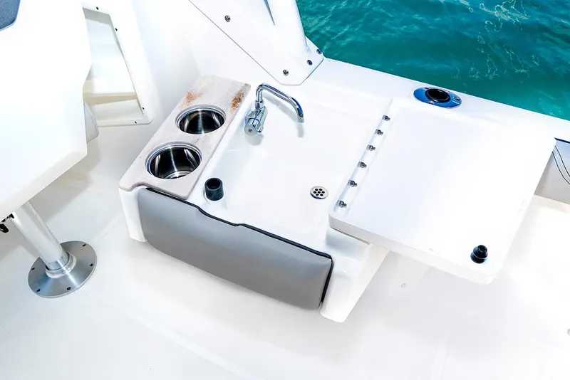 Slide: The Image of Manufacturer Provided Image: 2025 Pursuit DC 246 Dual Console boat sink and cup holders by the ocean. - 10