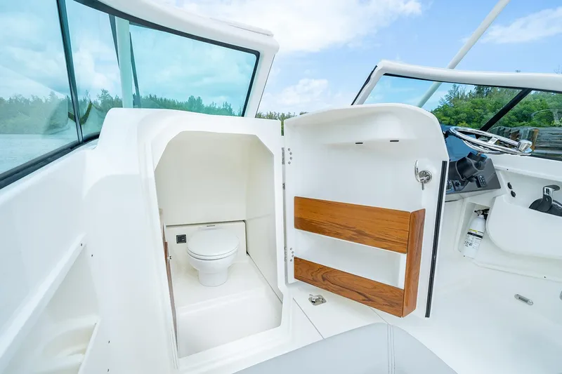 Slide: The Image of Manufacturer Provided Image: 2025 Pursuit DC 246 Dual Console boat interior with compact marine toilet. - 8