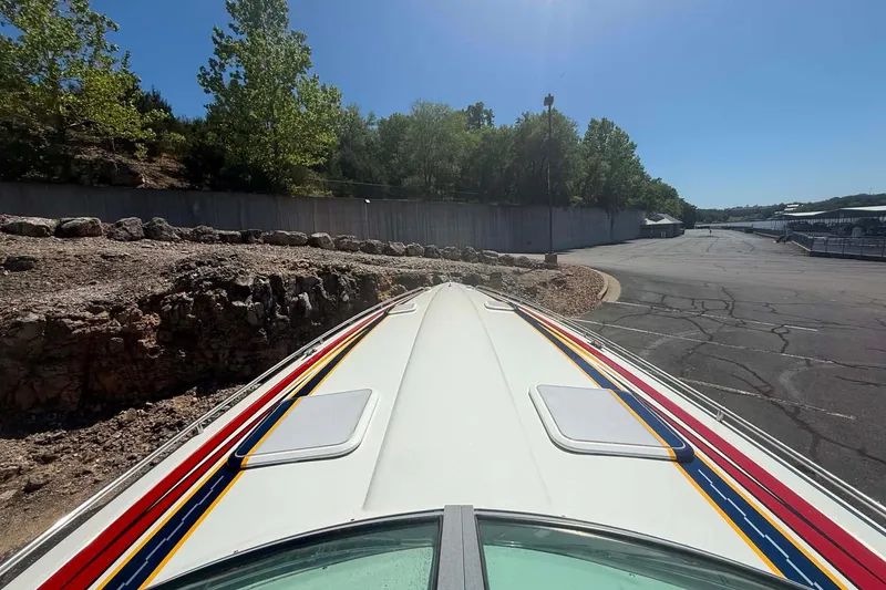 Slide: The Image of 2007 Formula 353 FASTech boat with colorful stripes, parked near a rocky shoreline. - 18
