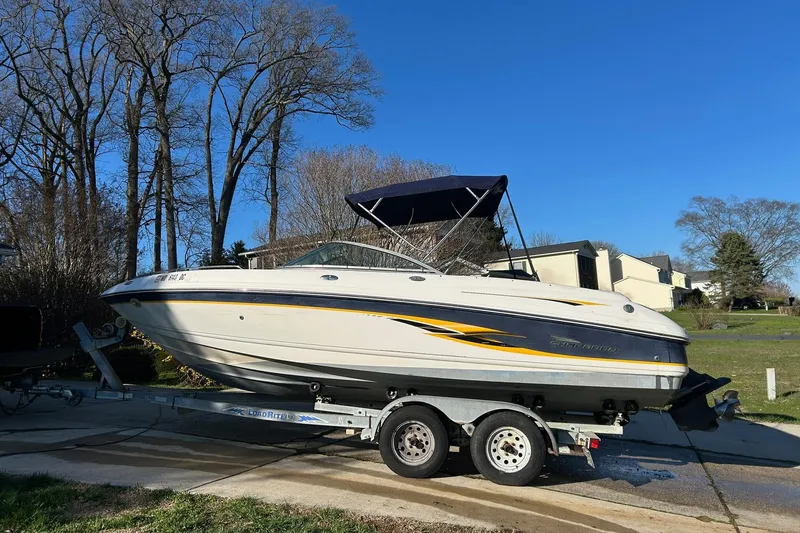 The Image of Chaparral 21 SSi 2003 boat on trailer, parked in suburban driveway under clear blue sky. - 0