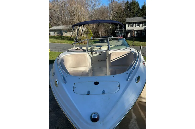 Slide: The Image of 2003 Chaparral 21 SSi boat with open bow seating and canopy, parked in a residential area. - 12