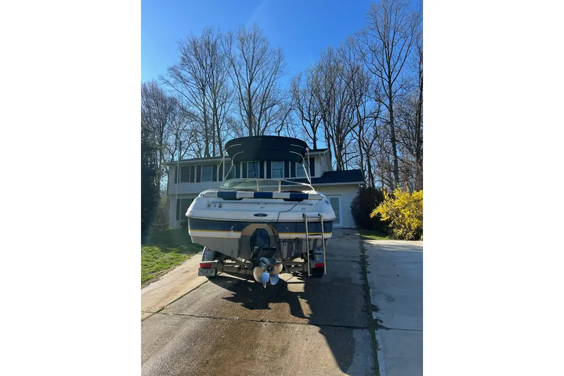 Slide: The Image of 2003 Chaparral 21 SSi boat parked in driveway, surrounded by trees and a house. - 13
