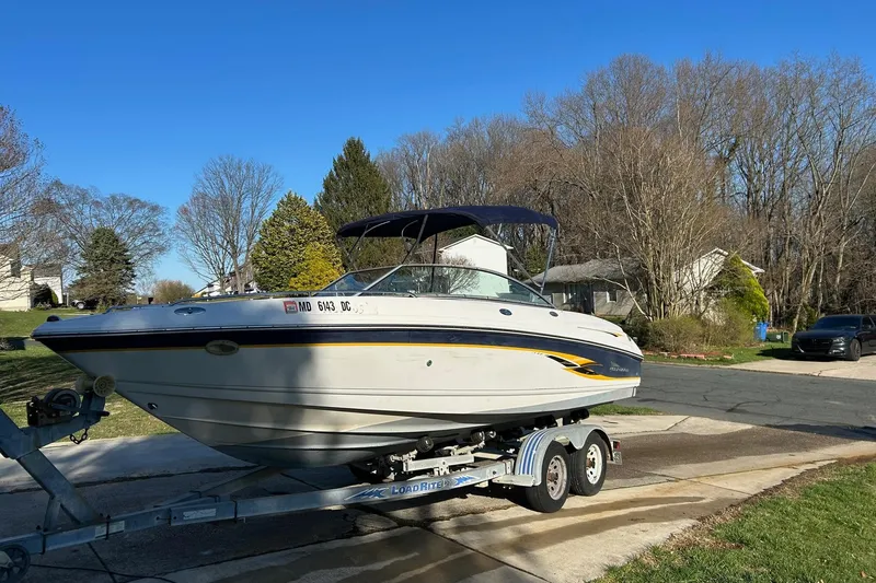 Slide: The Image of 2003 Chaparral 21 SSi boat on trailer, parked in suburban driveway under clear blue sky. - 2