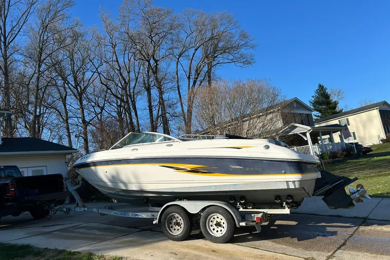 Slide: The Image of 2003 Chaparral 21 SSi boat on trailer, parked in residential driveway, surrounded by trees. - 5