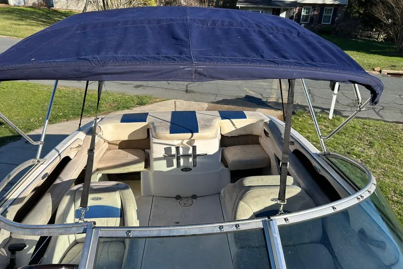 Slide: The Image of 2003 Chaparral 21 SSi boat with blue canopy and beige seating, parked on grass. - 8
