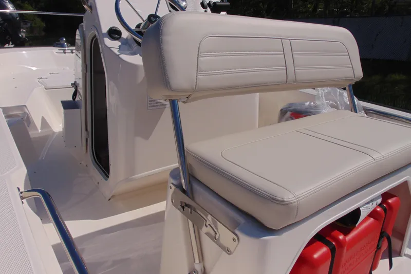 Slide: The Image of 2026 Boston Whaler 150 Montauk boat interior with cushioned seating and steering console. - 13