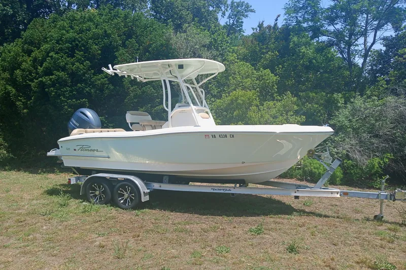 Slide: The Image of 2020 Pioneer 202 Islander boat on trailer, parked on grass with trees in background. - 2