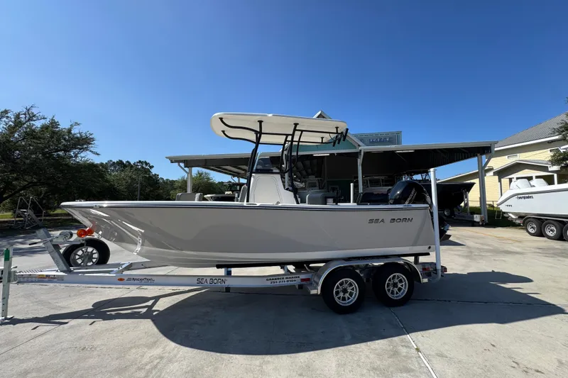 The Image of 2027 Sea Born LX21 Center Console boat on trailer, parked outdoors under clear sky. - 1