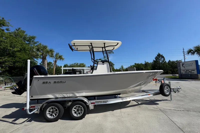 Slide: The Image of 2027 Sea Born LX21 Center Console boat on trailer under clear blue sky. - 8