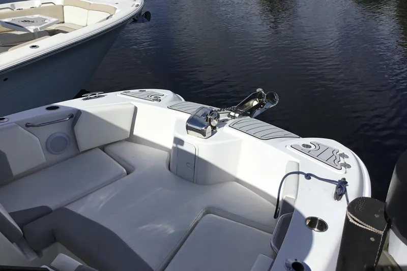 Slide: The Image of 2020 Twin Vee 240 DC GF boat interior with seating and anchor, docked on calm water. - 20