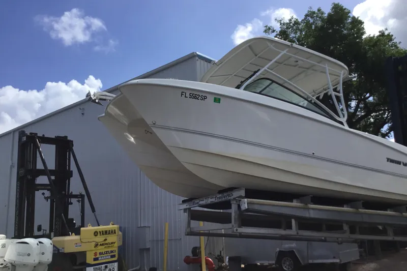 Slide: The Image of 2020 Twin Vee 240 DC GF boat on trailer, parked near a warehouse. - 23