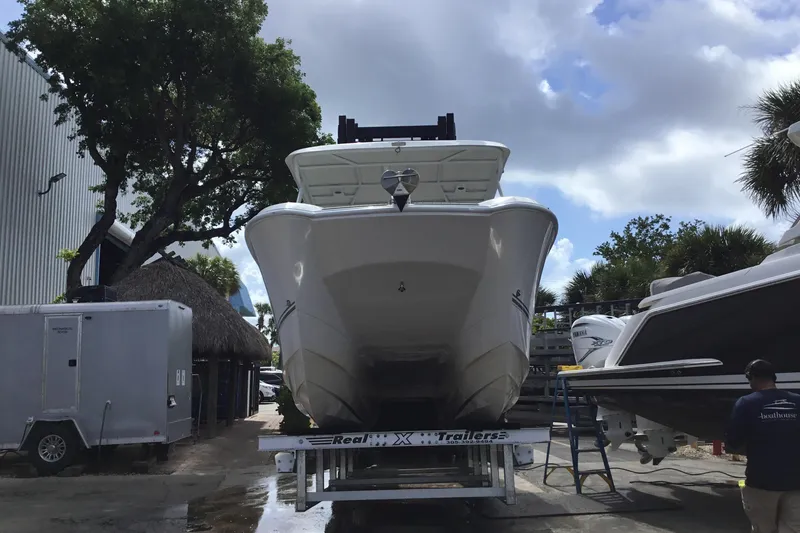 Slide: The Image of 2020 Twin Vee 240 DC GF boat on trailer, surrounded by trees and other boats. - 24